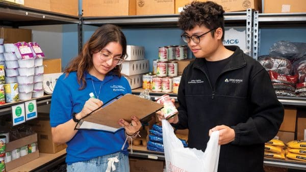 Two public health studies students packing groceries at the Harriet Lane Clinic's food pantry.