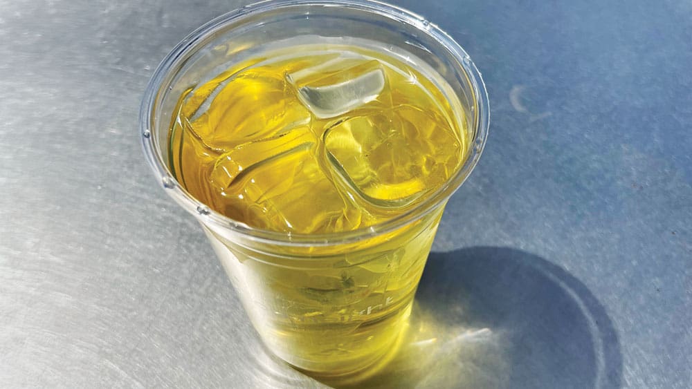top view of glass of iced green tea on metal table