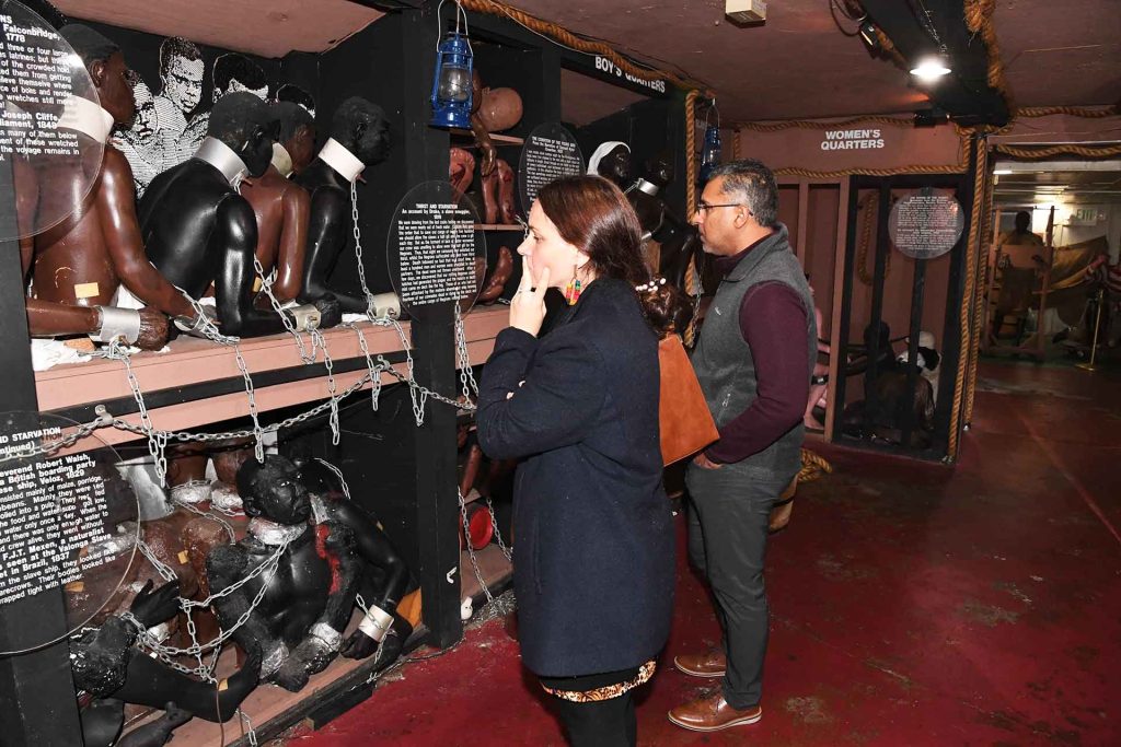 two people standing in front of wax statues showing slaves chained inside of a false boat