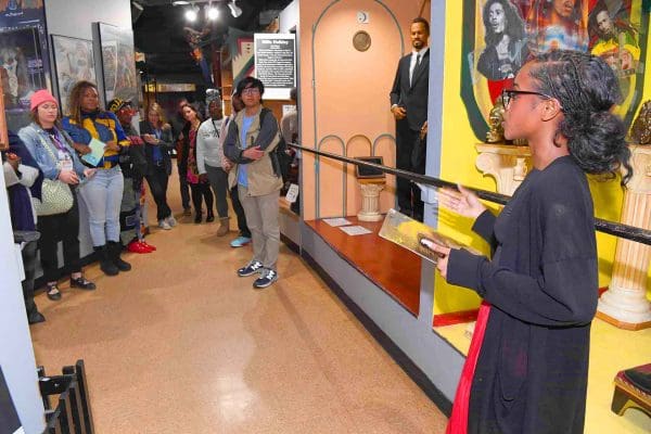 A student leading a walk through Great Blacks in Wax Museum exhibit