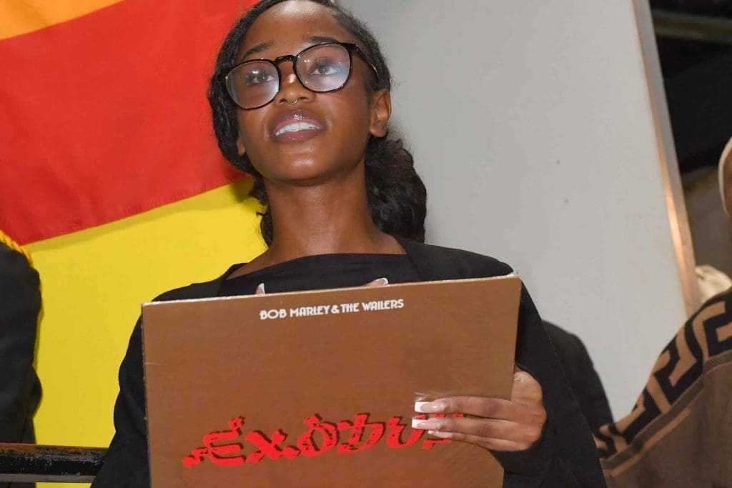 A young student holding a copy of the Bob Marley and the Wailers record "Exodus"