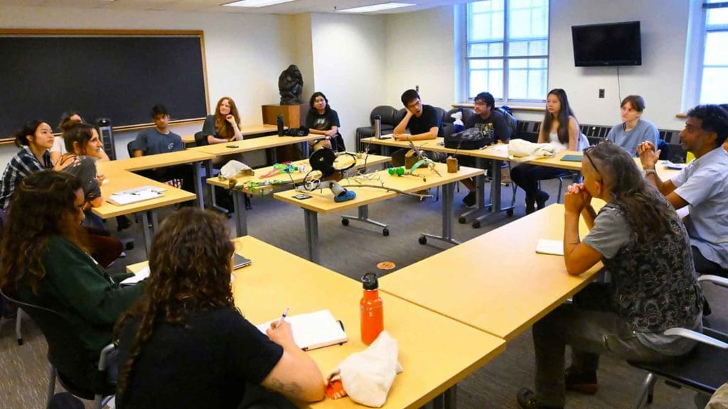 a wide shot of classroom with tables in square formed with assemblages in center on top of tables