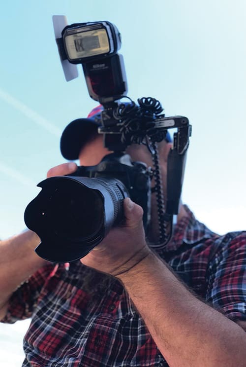 looking up at the extended lens of a camera, with Will Kirk hidden behind it