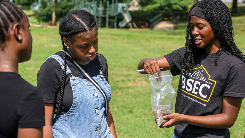 Ariana Strasser-King ’27, far right, holds a plastic bag of dirt as she discusses soil collection with students.