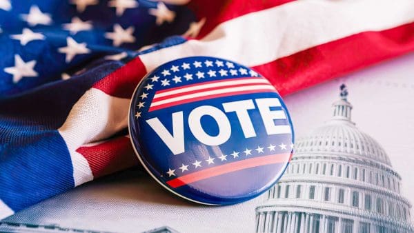 Photo of U.S. Capitol with American flag overlaying and a 'VOTE' button in the center.