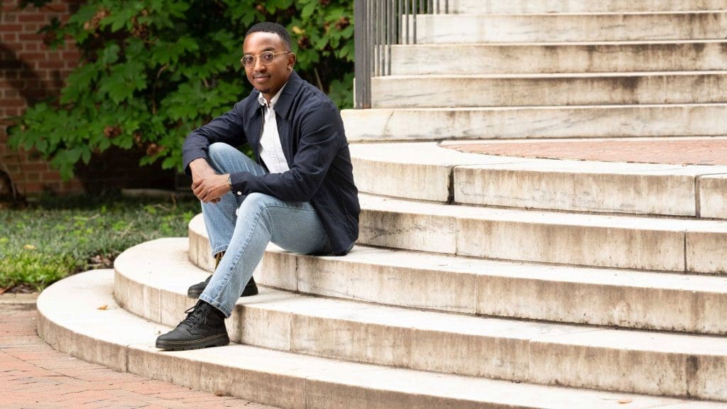 Kory Gaines sitting on marble steps on campus