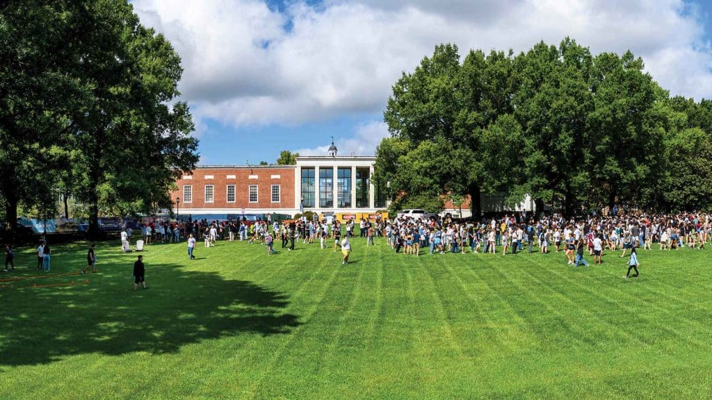 students outdoors on sunny day for t-shirt give away in front of Eisenhower library ("the beach")