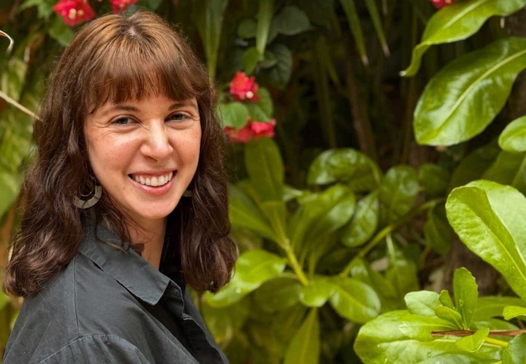 Jessica Croteau smiling and standing in front of greenery. 