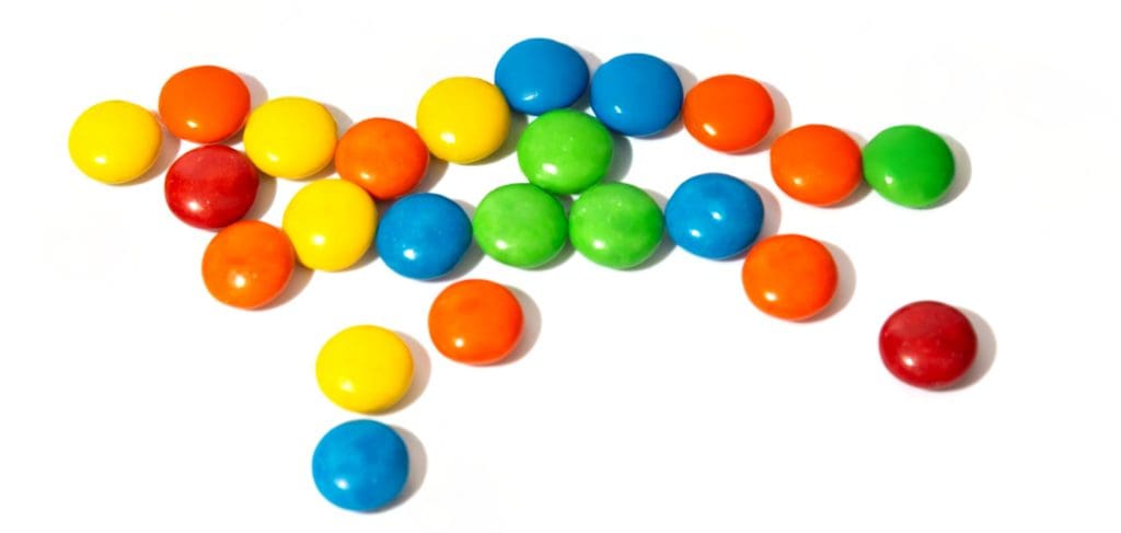 scattered M&Ms of red, orange, yellow, green, and blue