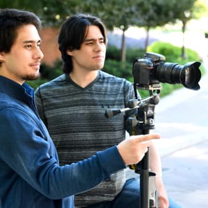 curtis and thomas holding a camera and tripod