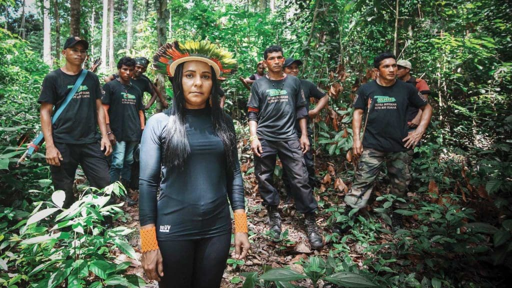 Indigenous leader Puyr Tembé and her team of standing together in rainforest.