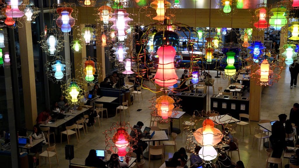 The Bloomberg Student Center main area lit by multicolored lamps. Students are seen studying.