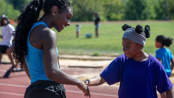 A JHU Volunteer shaking hands with one of the kids at the Run Baltimore event.