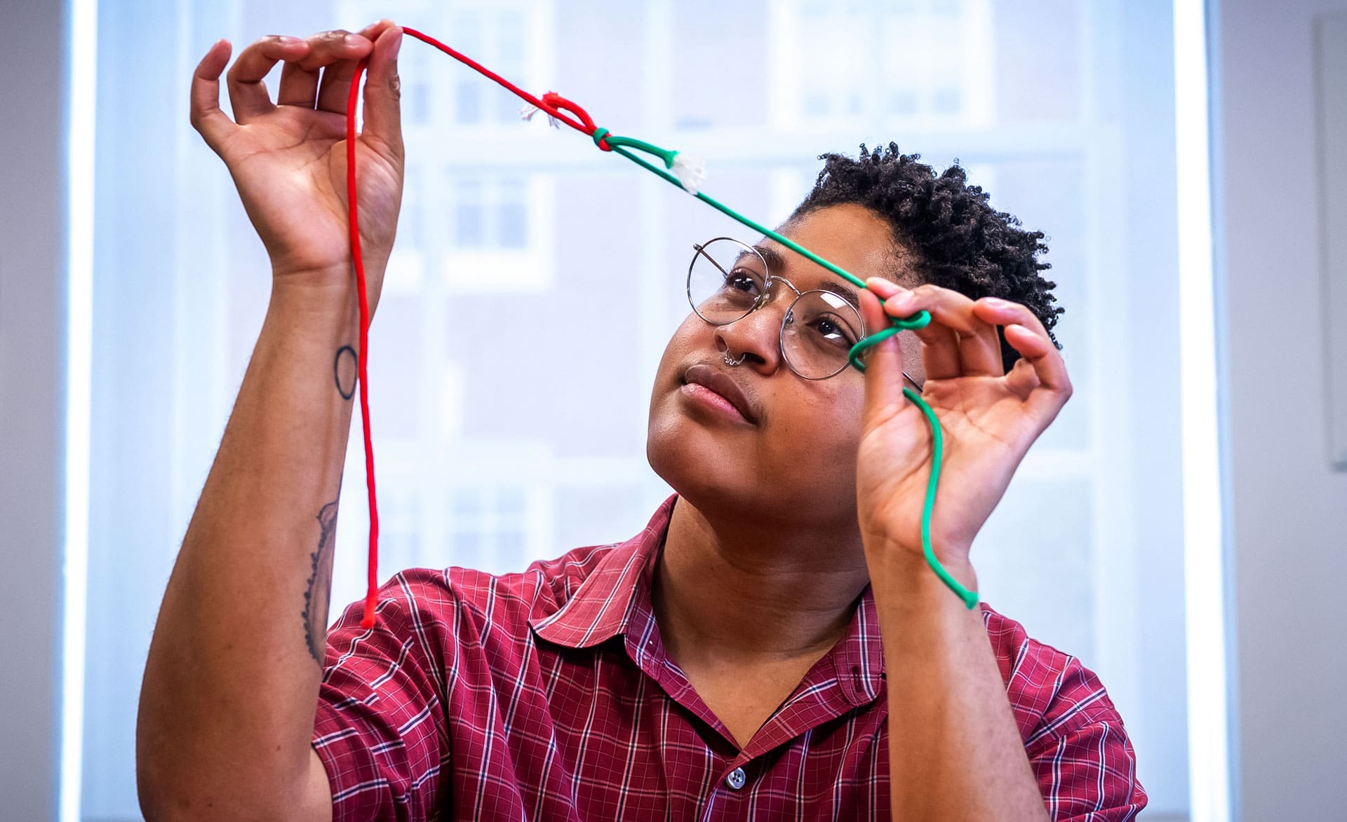 Sholei Croom looking at an example of a tied knot with contrasting red and green string.