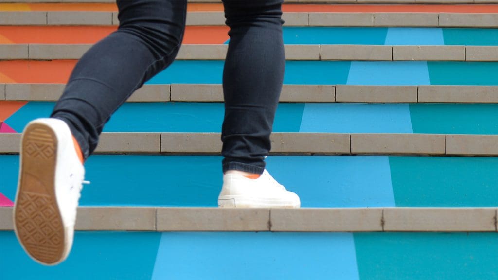 A closeup of someones legs walking up blue stairs.