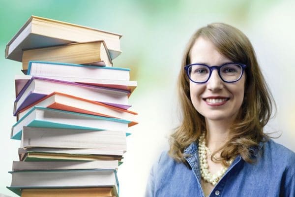 On the left is a pile of books, on the right is Stephanie Gamble