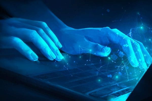 Illustration of hands typing on a laptop lit by the neon blue of the screen.